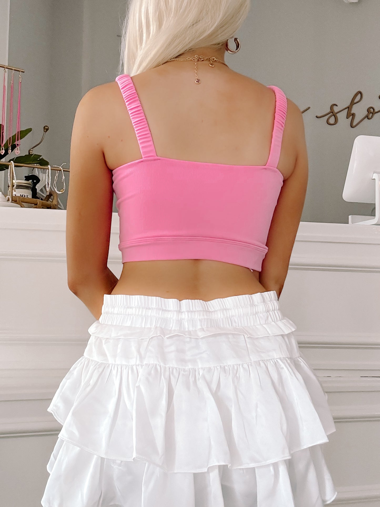 Pink crop top and white ruffled mini skirt, back view.