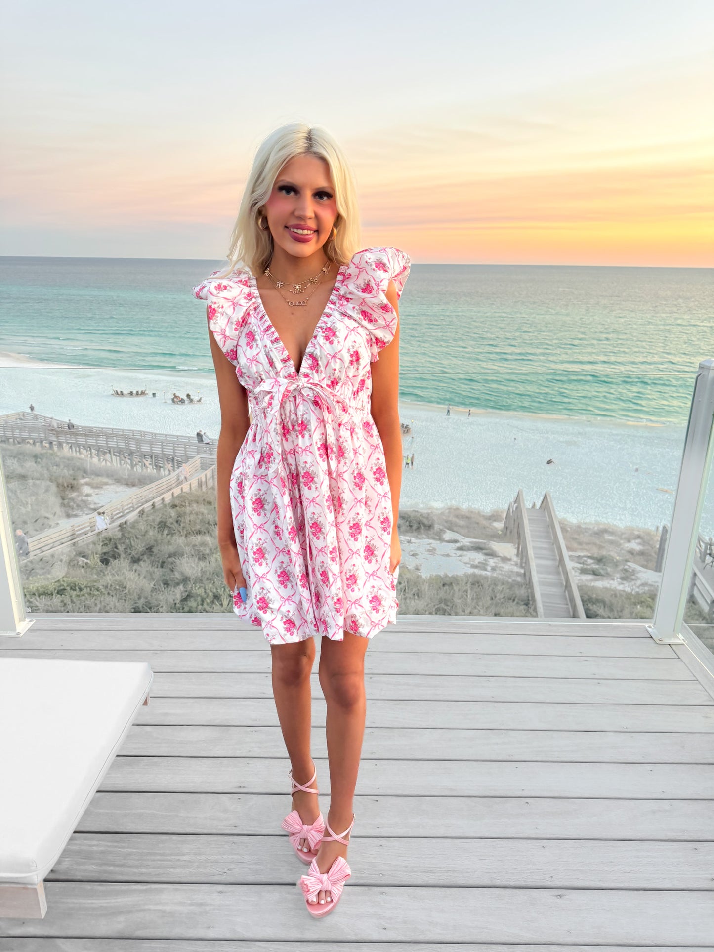 Floral mini dress on a beachside deck at sunset.