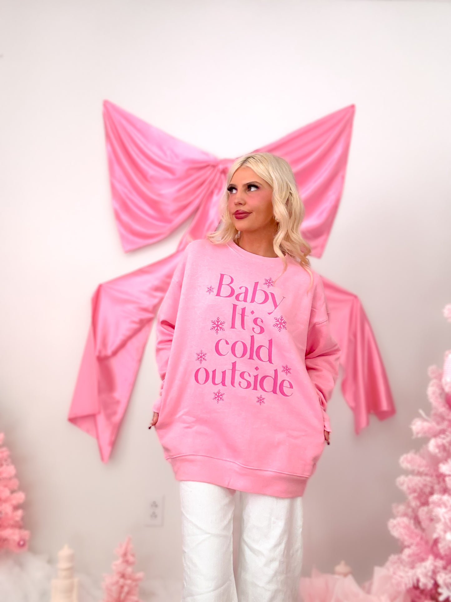 Close-up of the front of the pink crewneck, highlighting the hot pink "Baby It's Cold Outside" text and snowflake print.