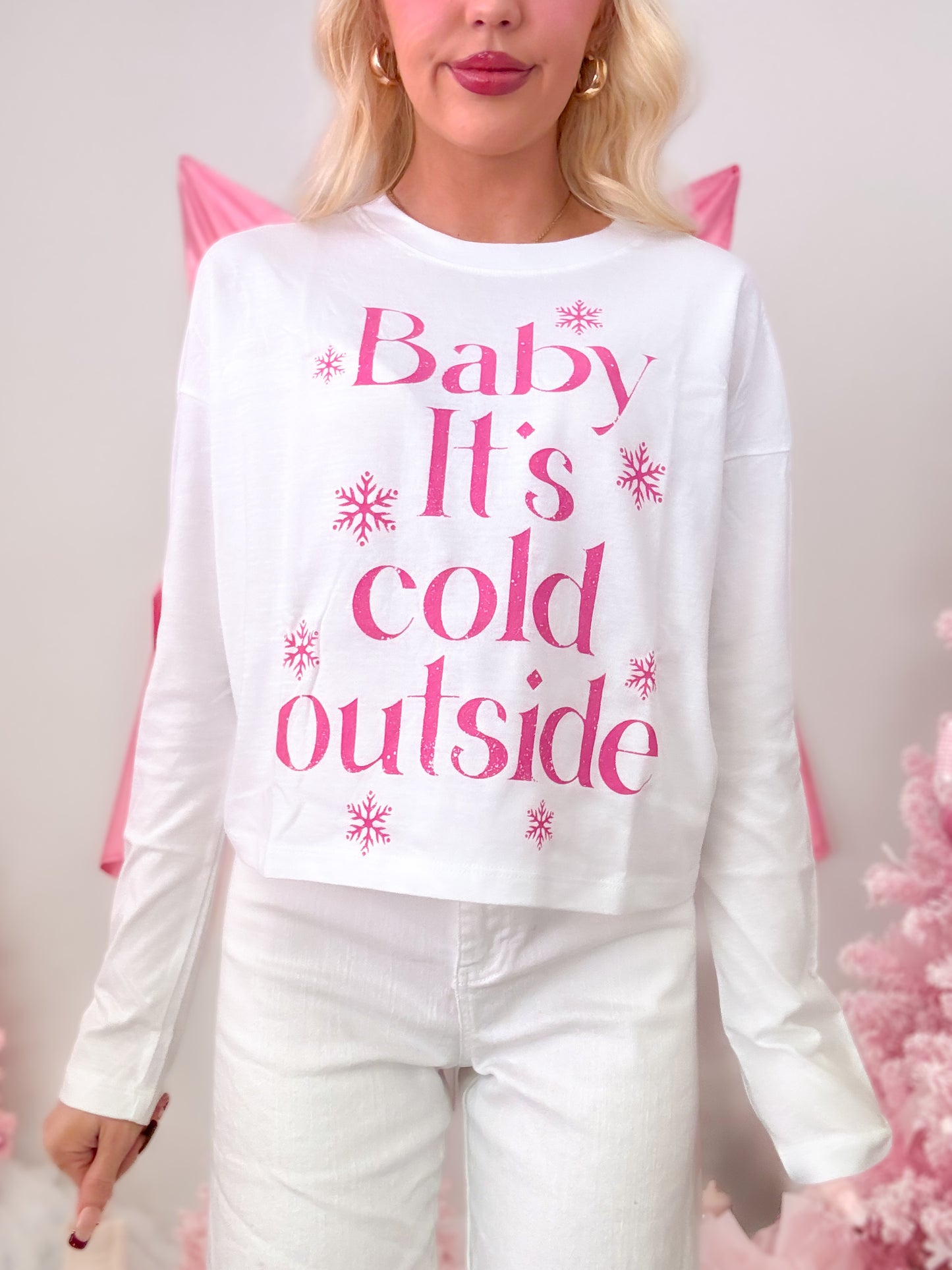 White short-sleeve t-shirt with a seasonal hot pink graphic that reads 'Baby It's Cold Outside,' modeled on figure.