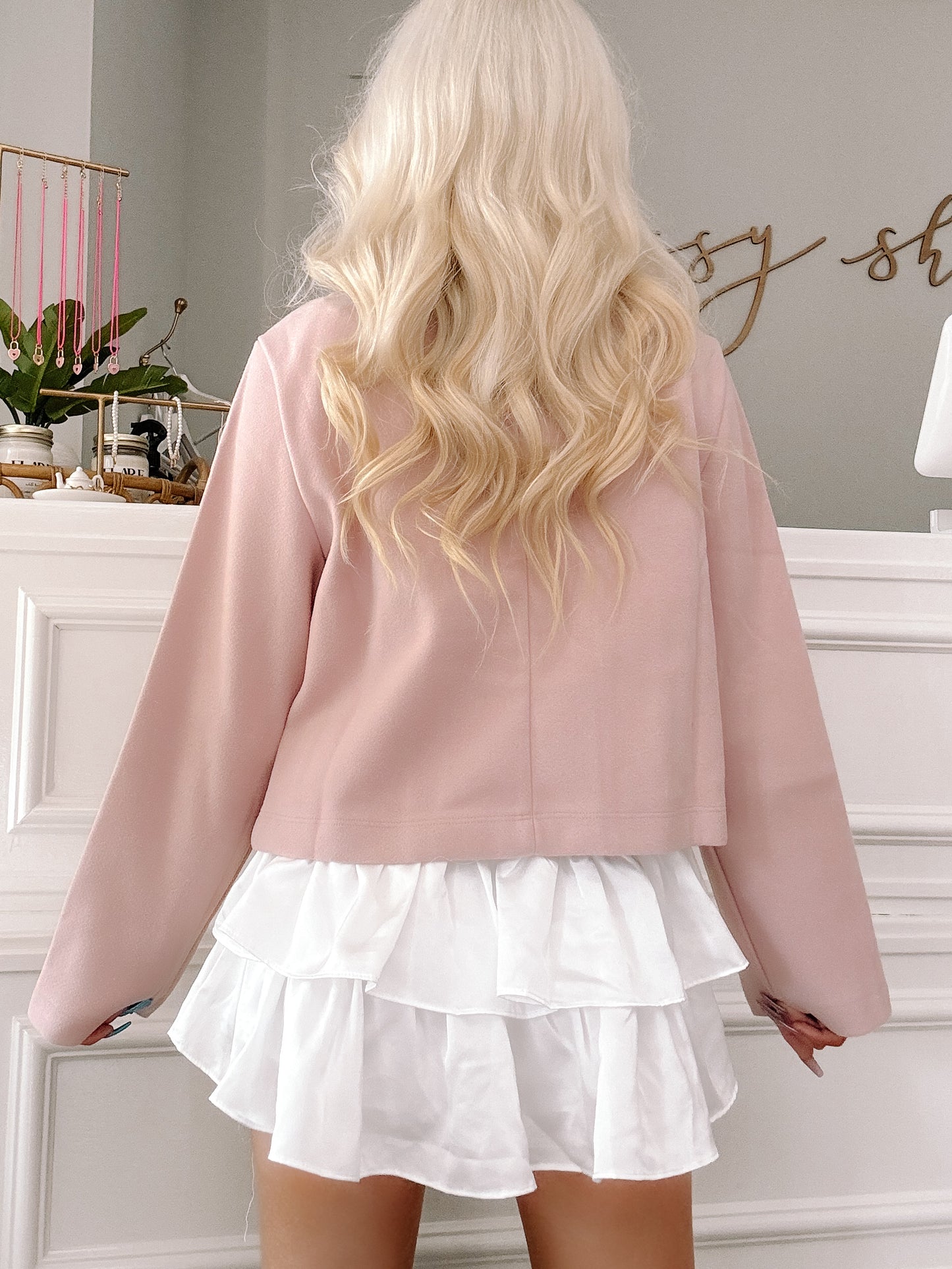 Dusty rose cropped blazer with long sleeves, shown from the back, layered over a white ruffled mini skirt.
