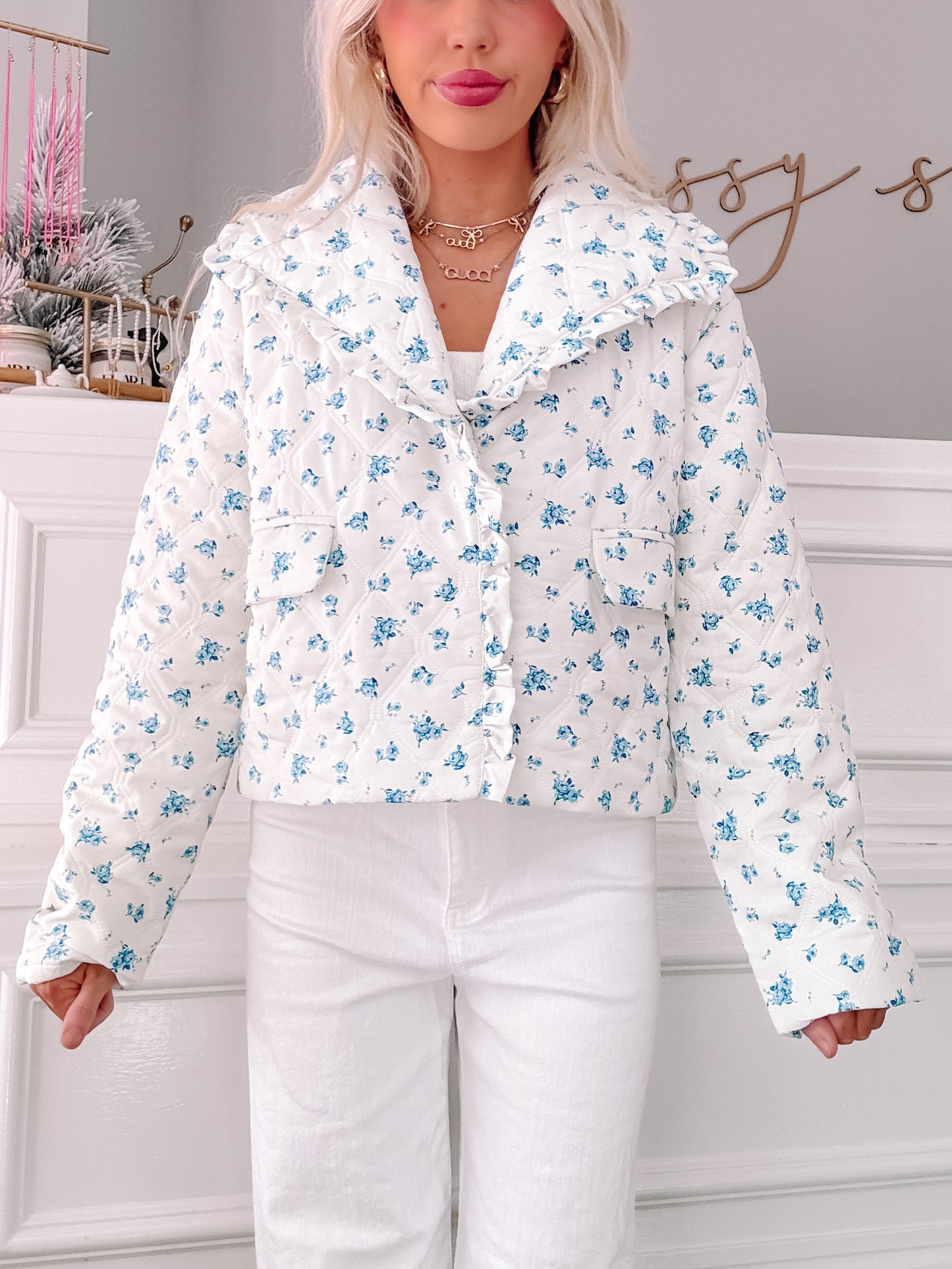 White quilted jacket with blue floral print, featuring a ruffled collar.