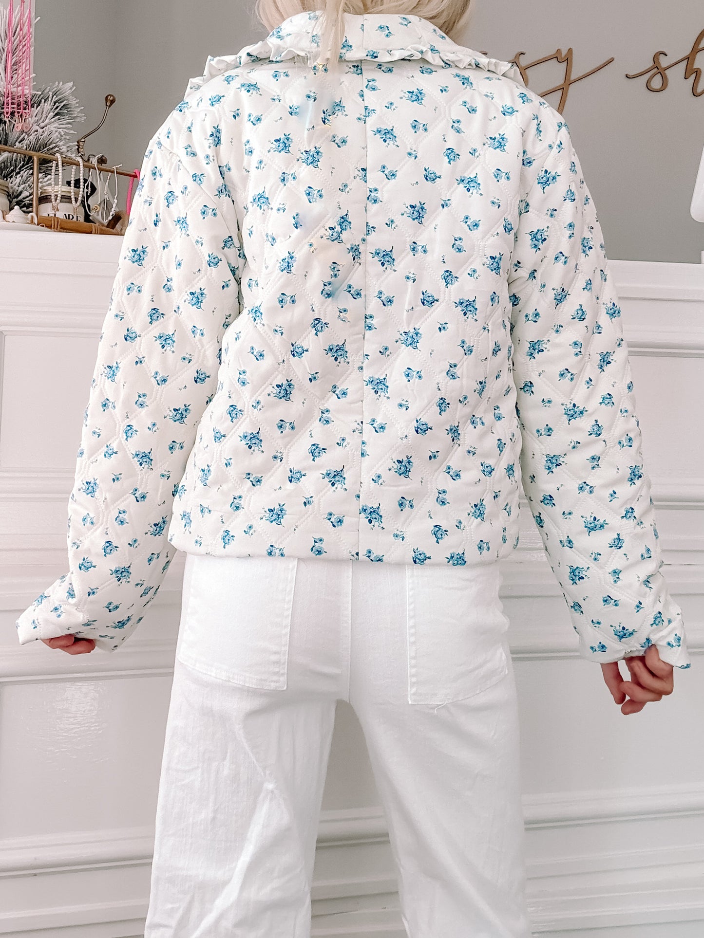 White quilted jacket with a blue floral print, shown from the back.
