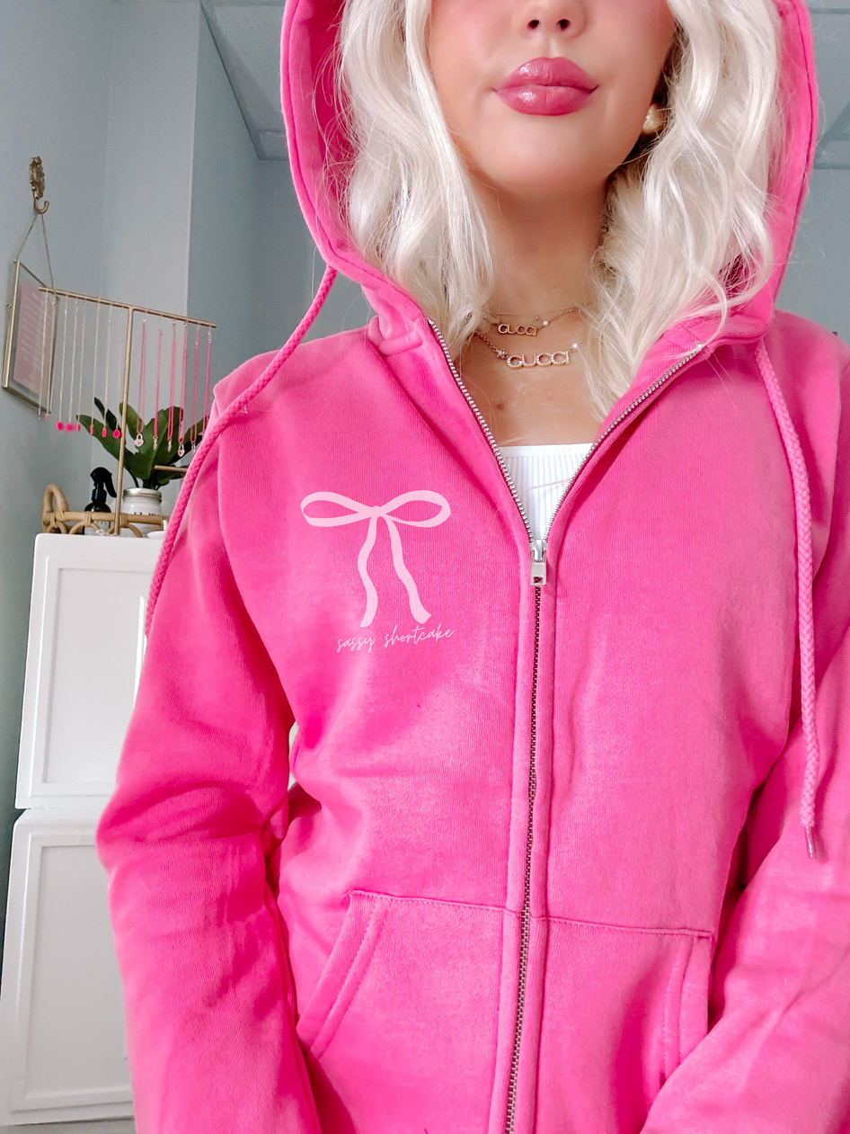 Hot pink zip-up hoodie featuring a bow design and "sassy shortcake" text.