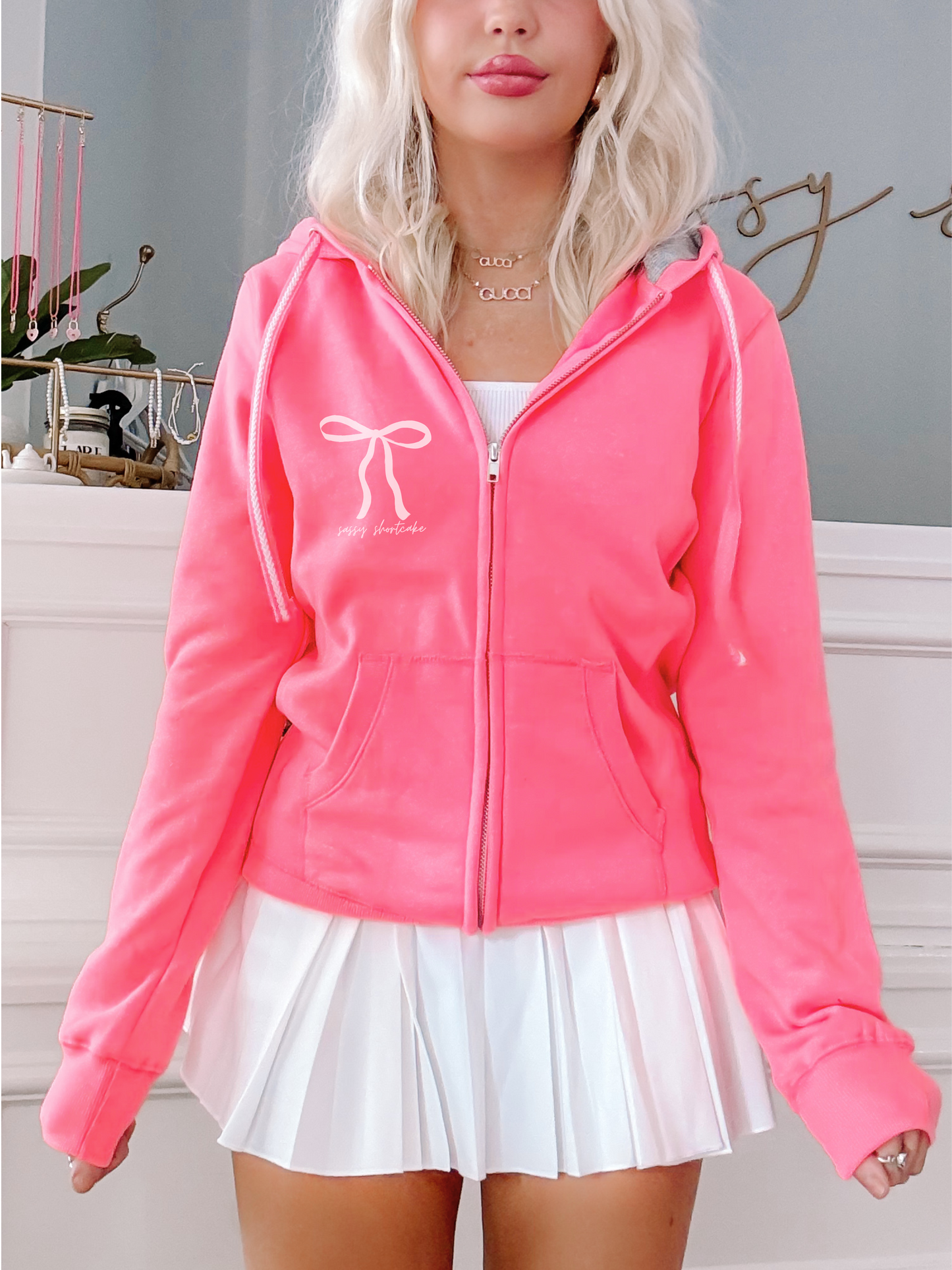 Neon pink zip-up hoodie, bow detail, "Sassy Shortcake" logo.