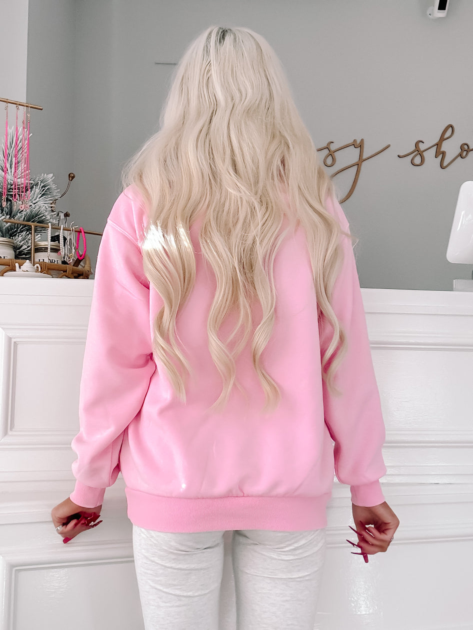 Pink quarter-zip sweatshirt, shown from the back, in a shop setting.