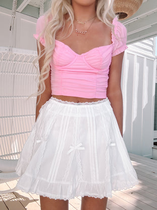 Model in the Bows & Lace white mini skirt with lace trim and bow ribbon accents.