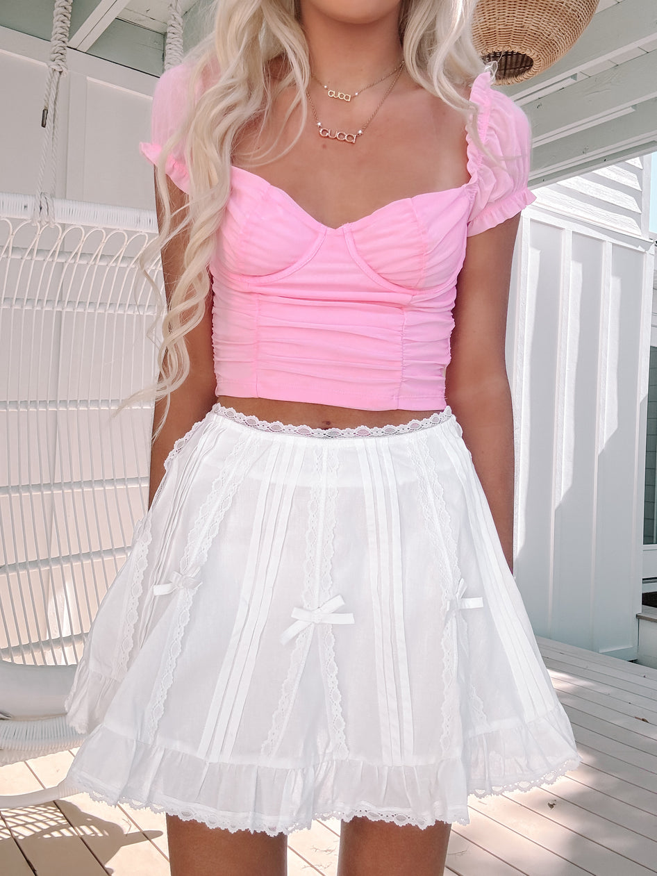 Model in the Bows & Lace white mini skirt with lace trim and bow ribbon accents.