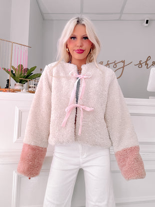 Cream sherpa jacket with blush pink cuffs and satin ribbon tie.
