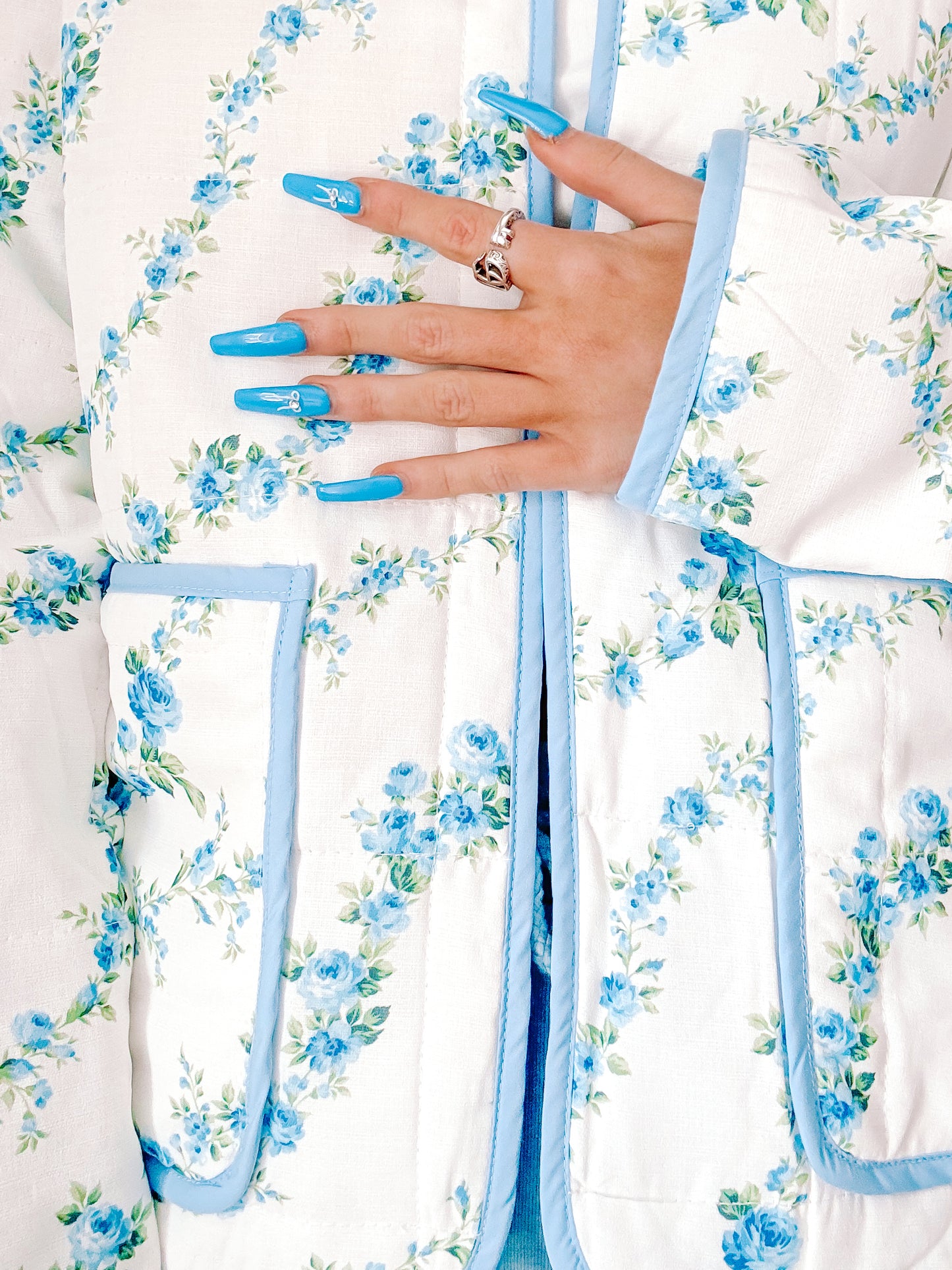 Blue floral quilted jacket detail shot, showcasing a light blue trim and delicate rose print.