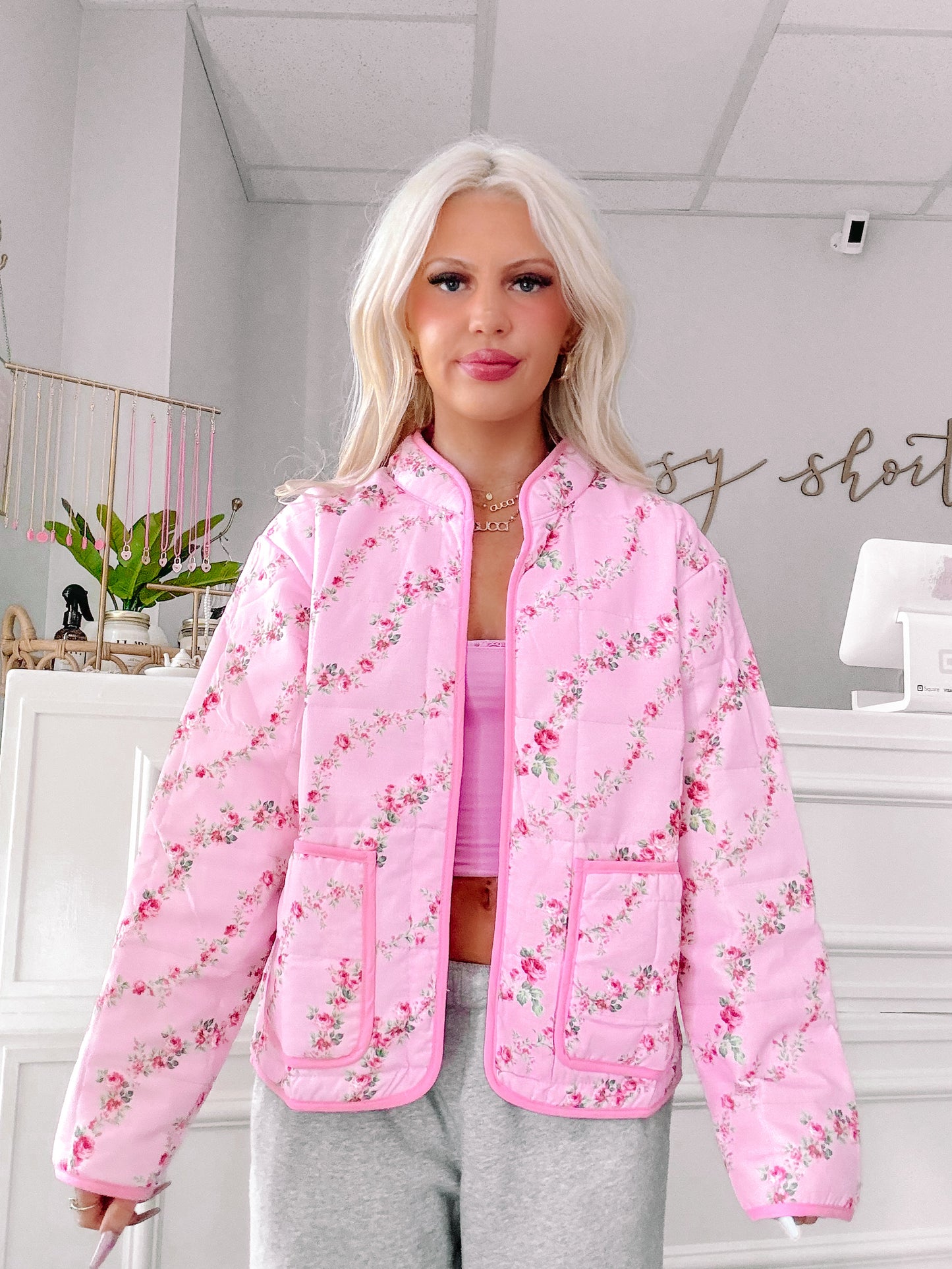 Pink quilted jacket with a delicate floral print, shown on a model.