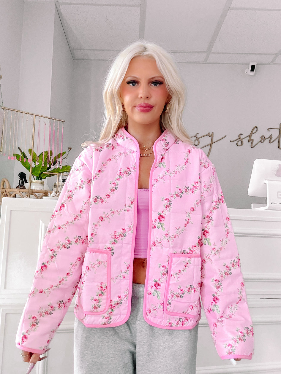 Pink quilted jacket with a delicate floral print, shown on a model.