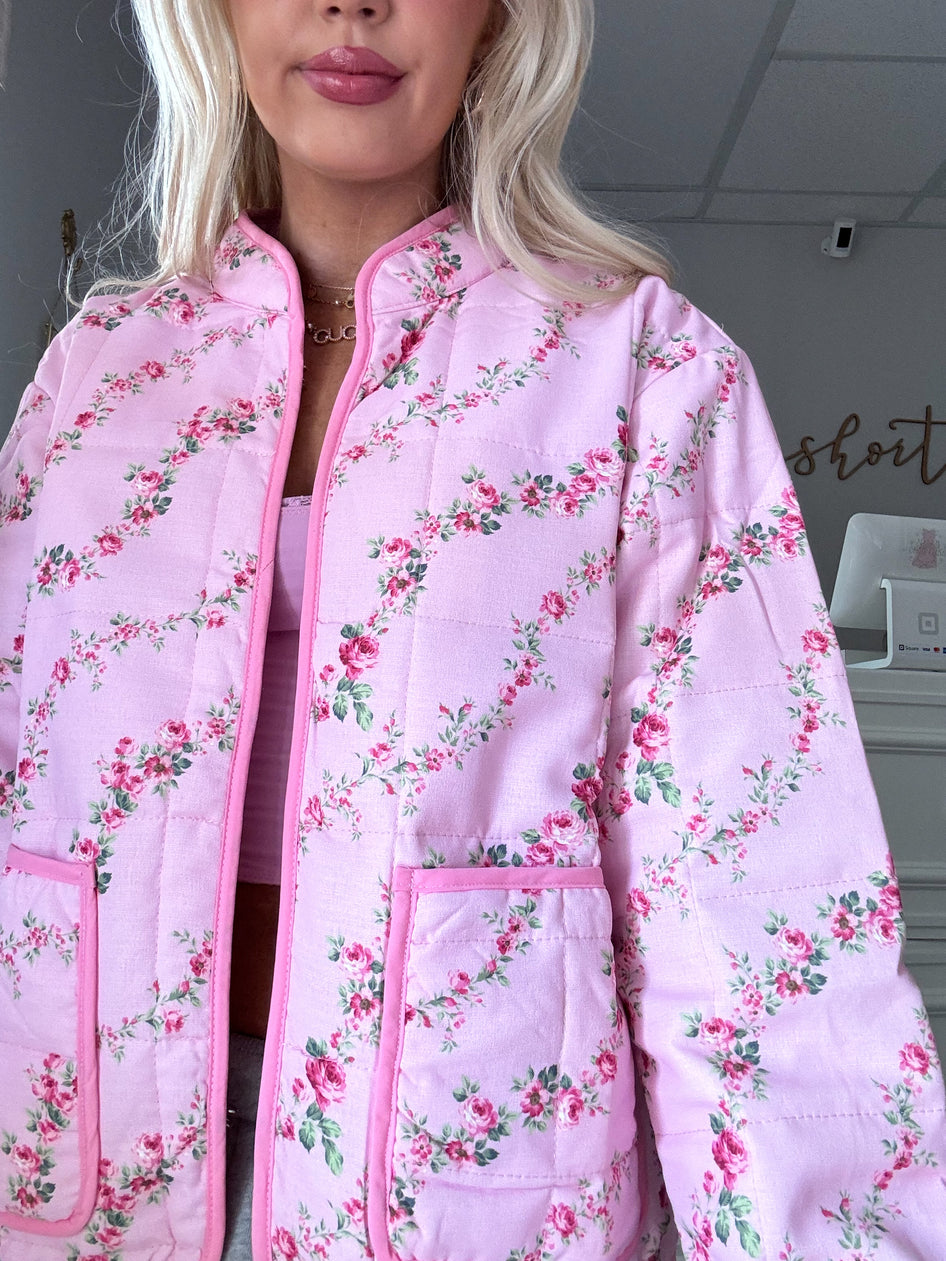 Pink quilted jacket with a delicate floral pattern, featuring patch pockets.