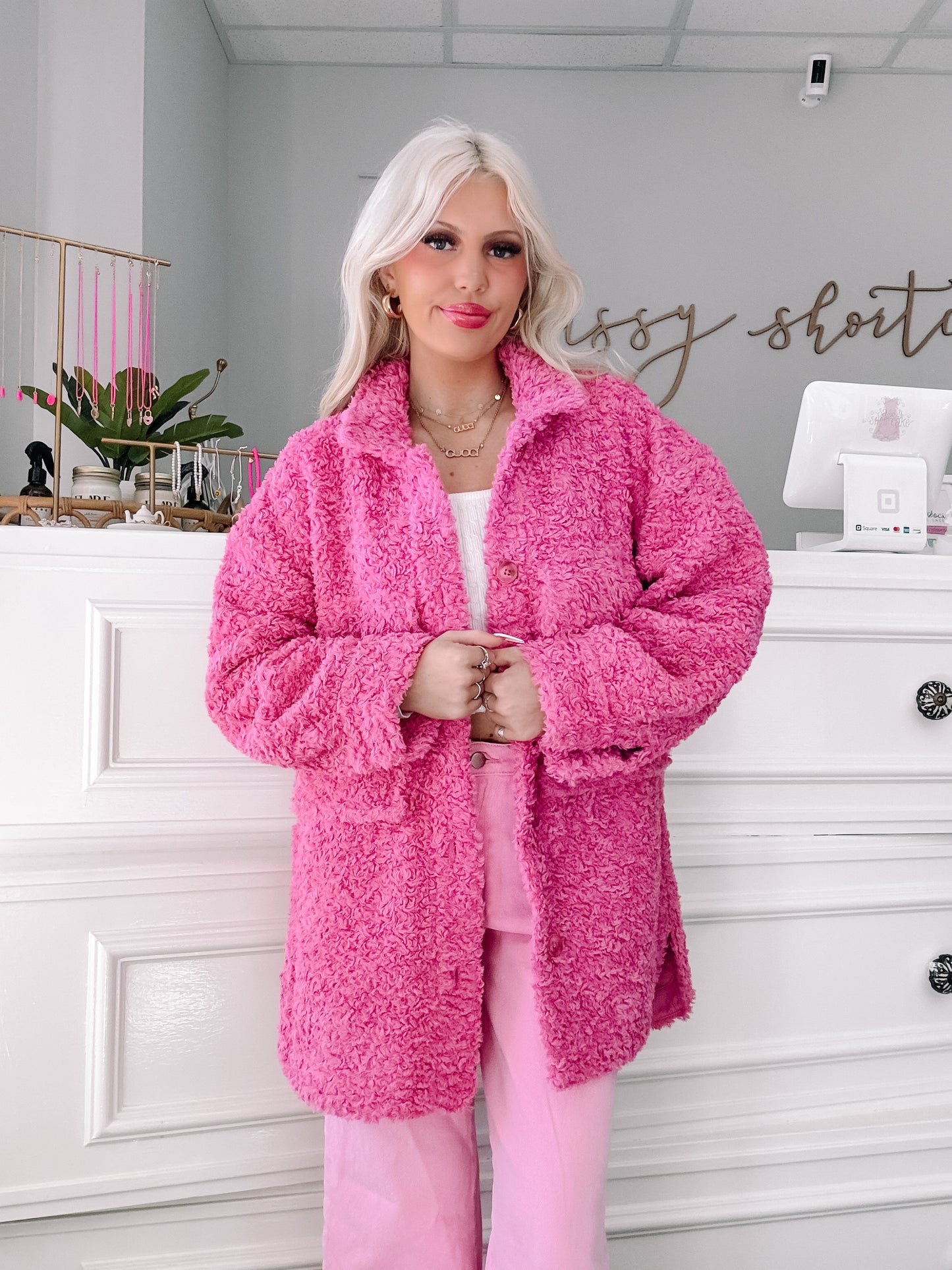 Fuzzy pink jacket styled with matching pants, worn indoors against a white backdrop.