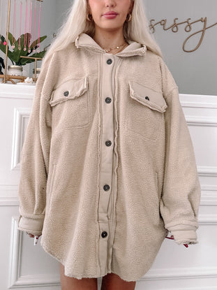 Cream-colored fuzzy shacket, button-front, oversized fit, modeled against a white wall.
