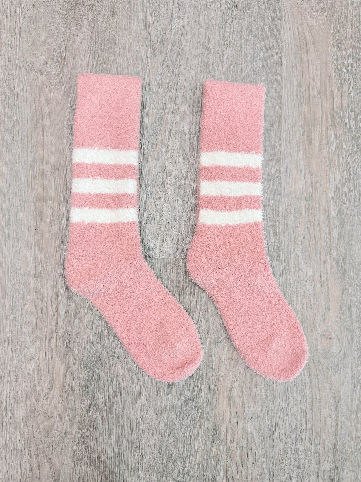 Fuzzy pink socks with white stripes for cozy comfort.