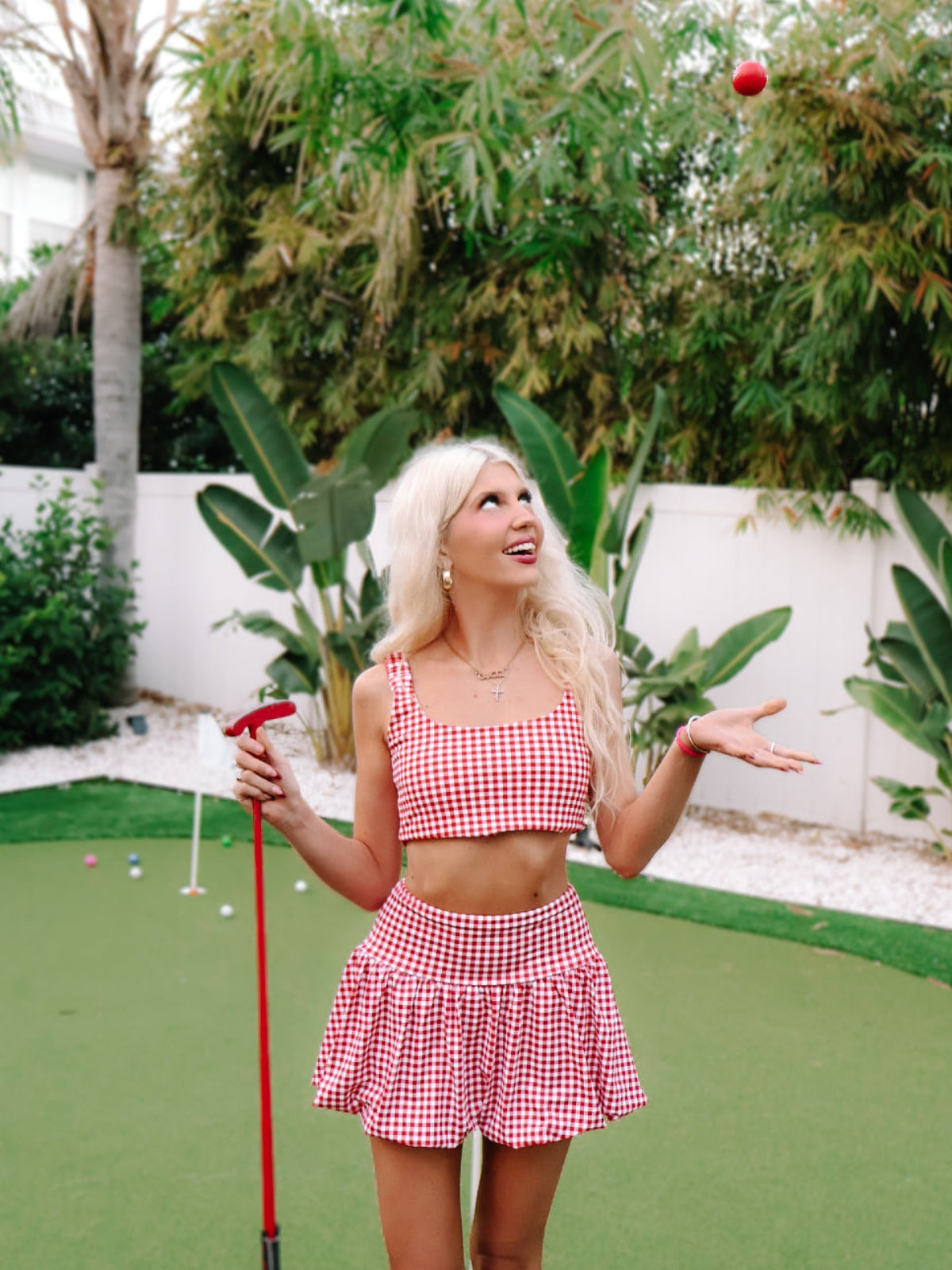 Game for Gingham Bubble Skirt by Sassy Shortcake - Woman in a red and white checkered outfit playing mini golf.