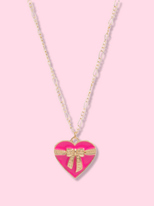 Pink heart pendant necklace with gold chain and bow detail on a pink background.