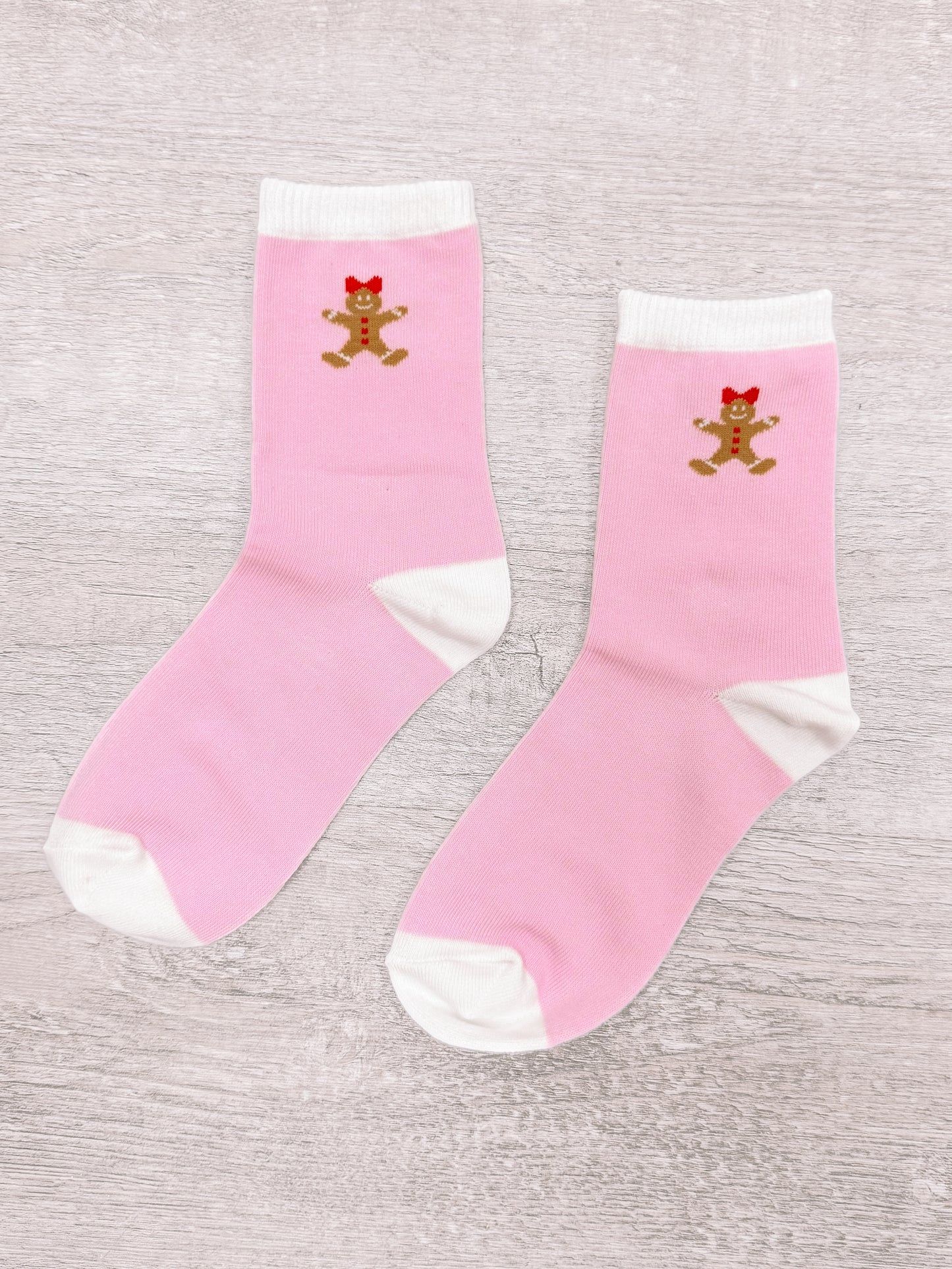 Pink gingerbread socks with white trim, featuring adorable gingerbread person design.
