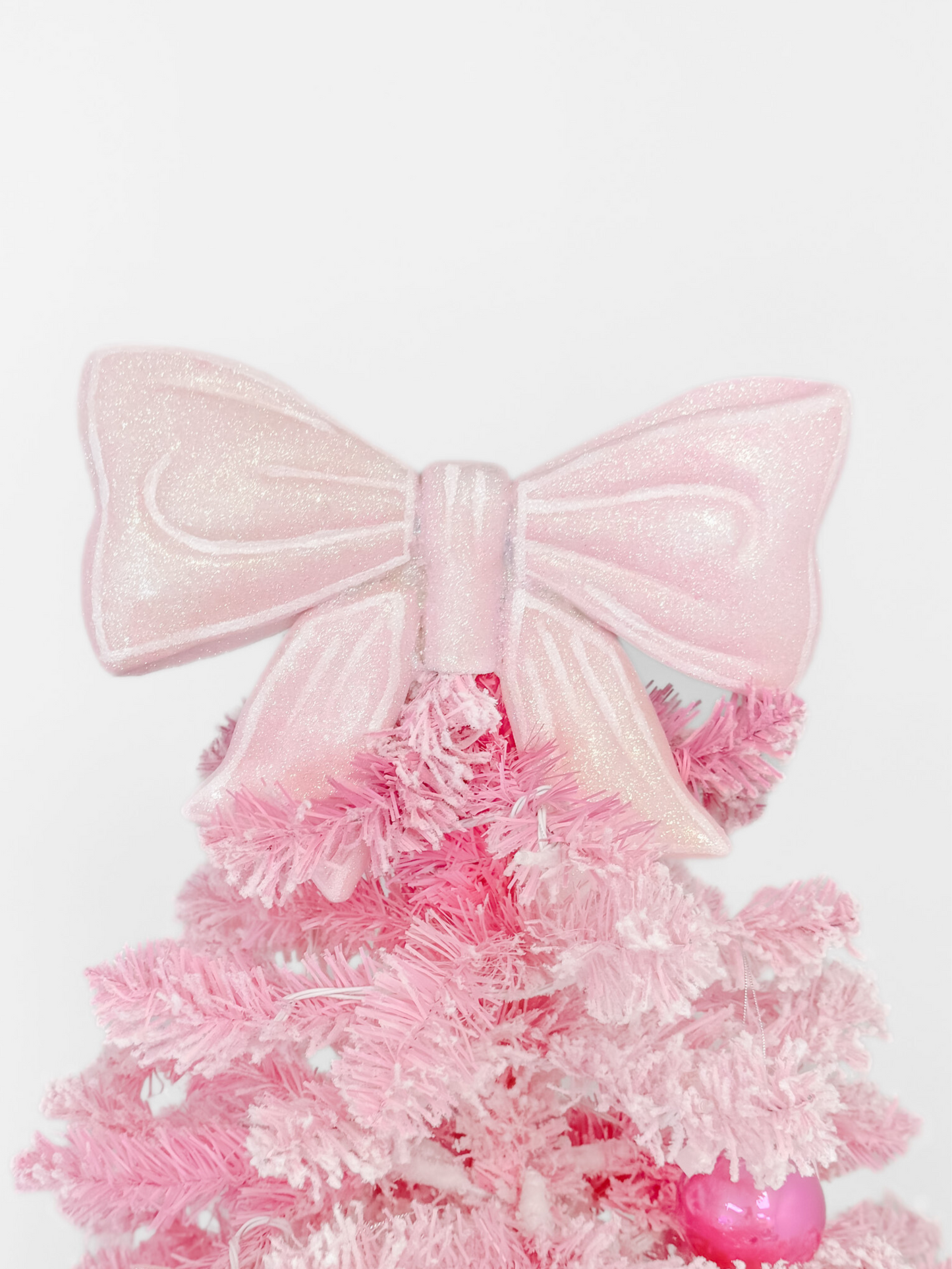 Pink glitter bow tree topper for a festive Christmas tree.