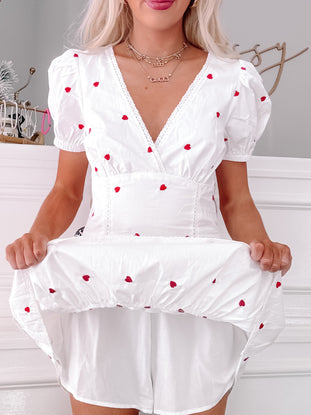 White mini dress with puff sleeves and scattered red heart embroidery; shown on model.
