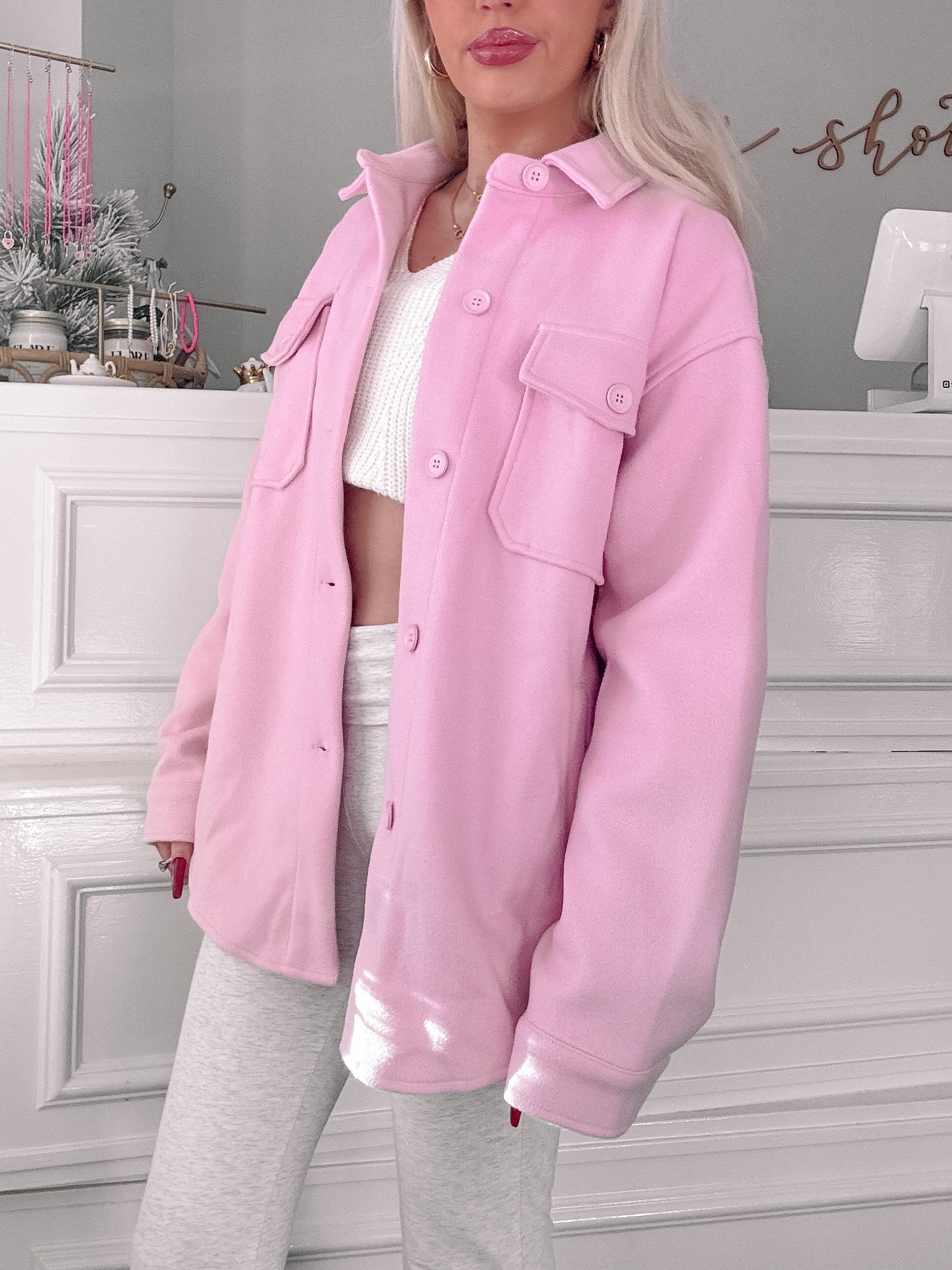 Soft pink oversized shacket, button-front, modeled indoors against white paneling.