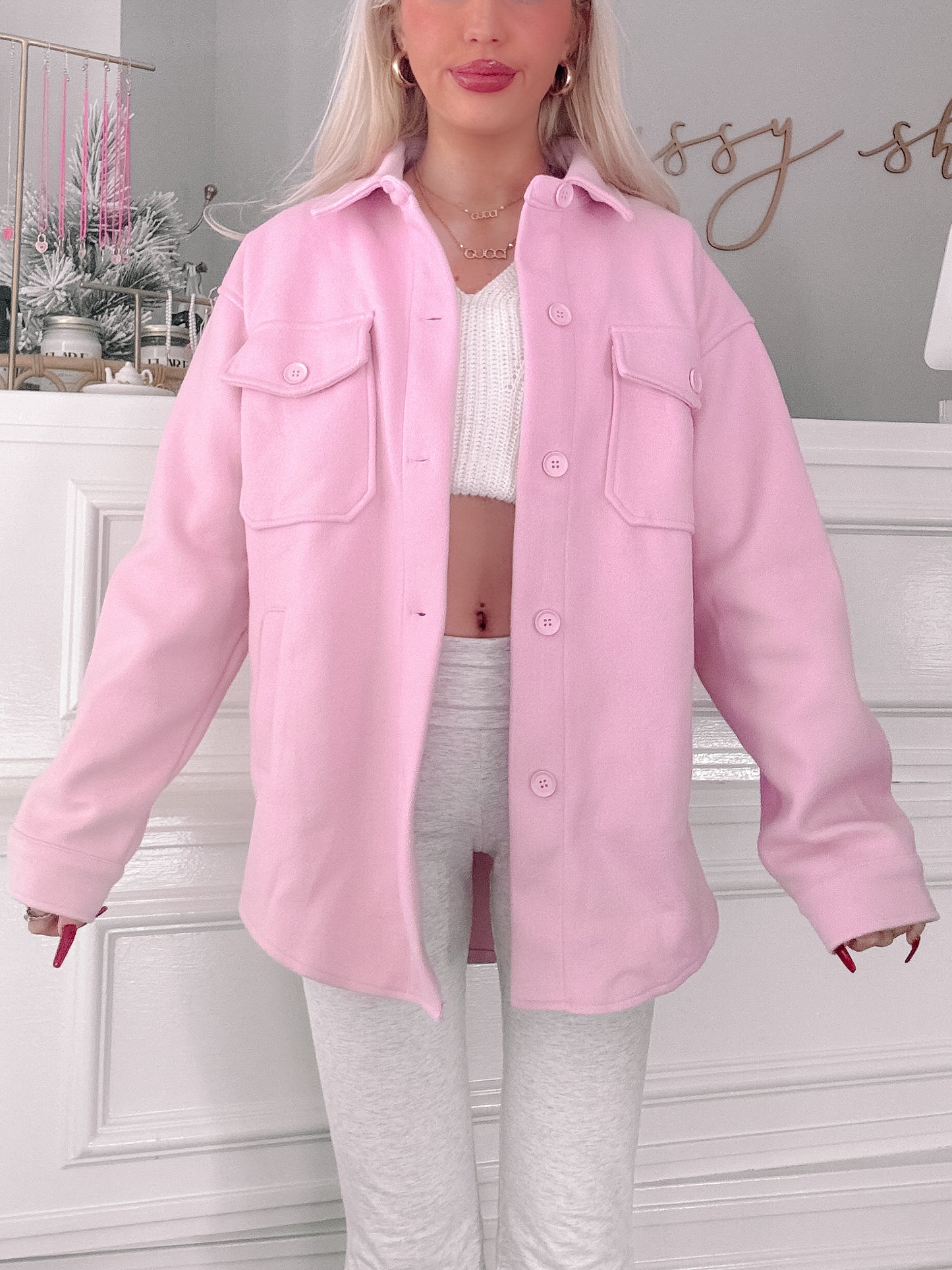 Pink button-up shacket styled over a white cropped sweater and gray leggings.