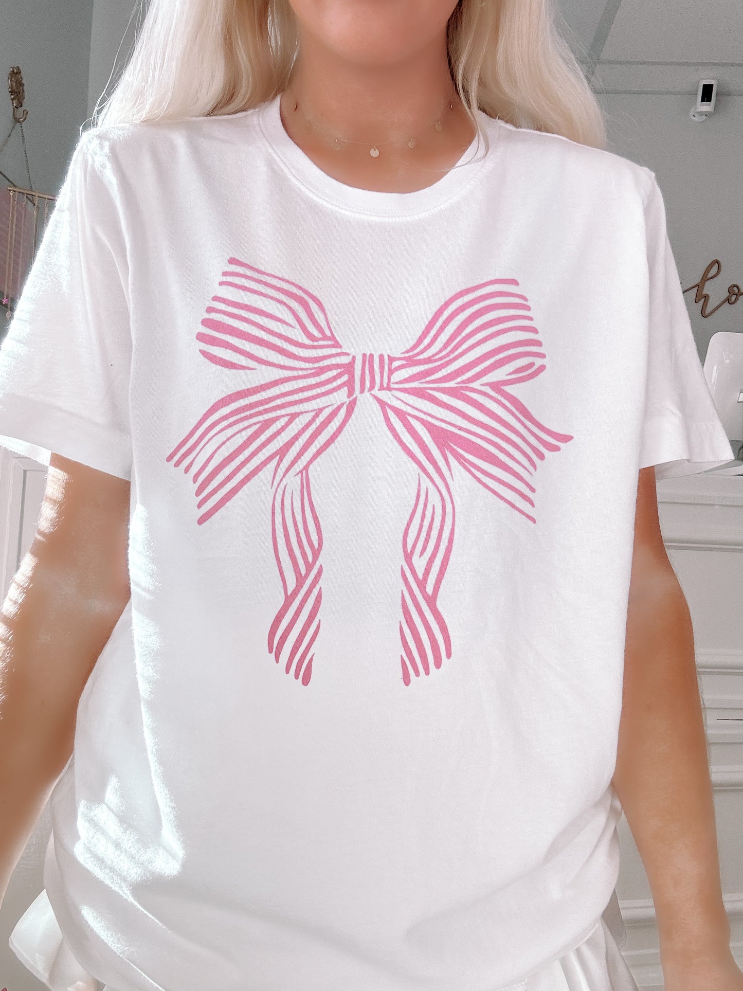 Pink striped bow graphic on a white cotton tee shirt.