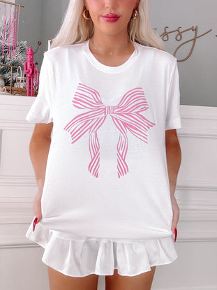 White tee with pink striped bow design; ruffle hem detail.