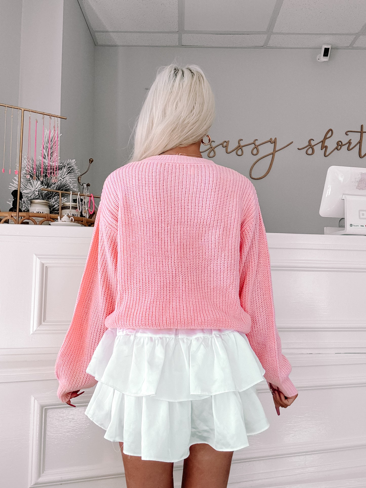 Pink knit sweater with balloon sleeves, shown from the back, paired with a white tiered skirt.