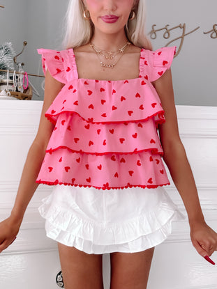 Pink tiered ruffle top with red hearts, perfect for Valentine's Day.