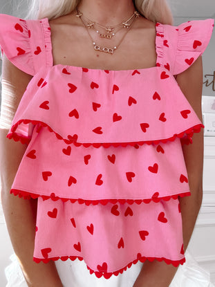 Pink tiered top with red hearts, scalloped trim