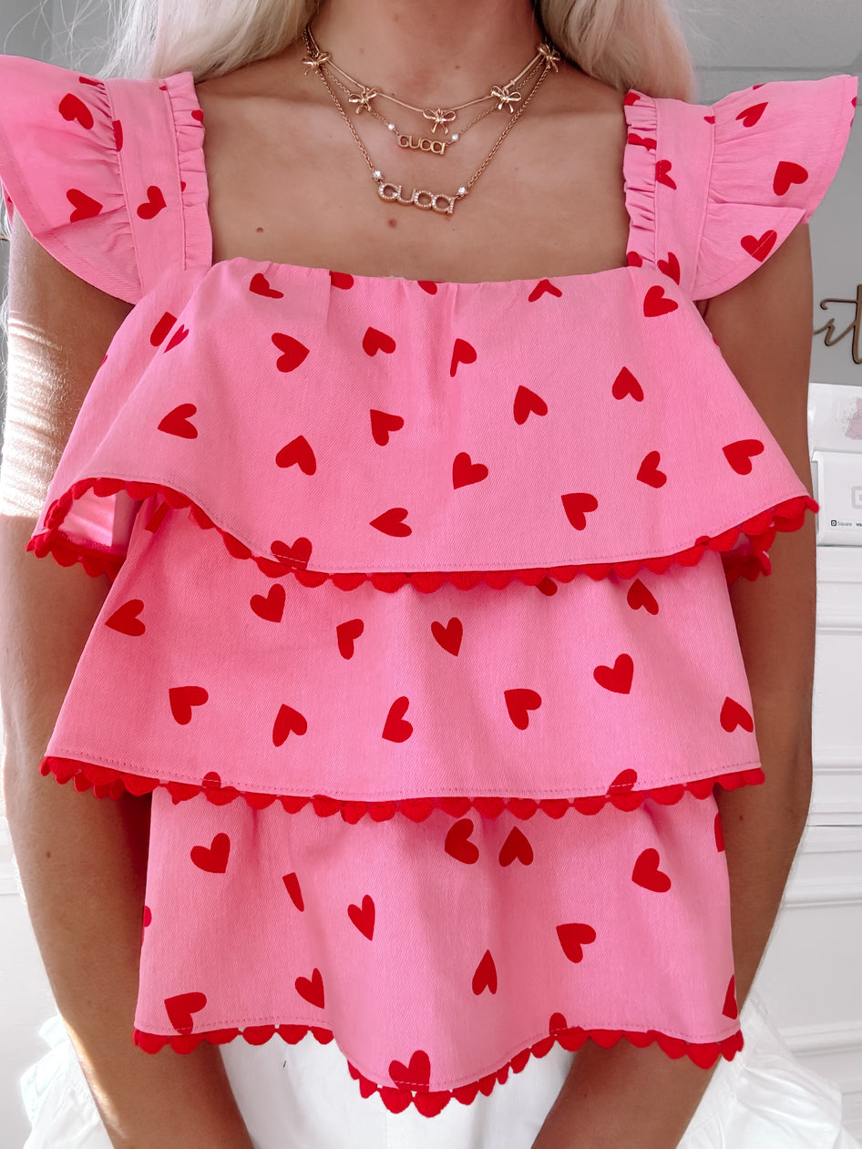 Pink tiered top with red hearts, scalloped trim
