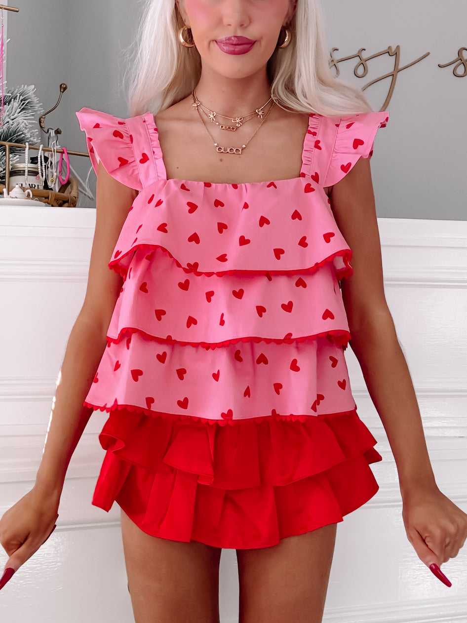 Pink tiered ruffle top with red hearts, layered over a red ruffled skirt.