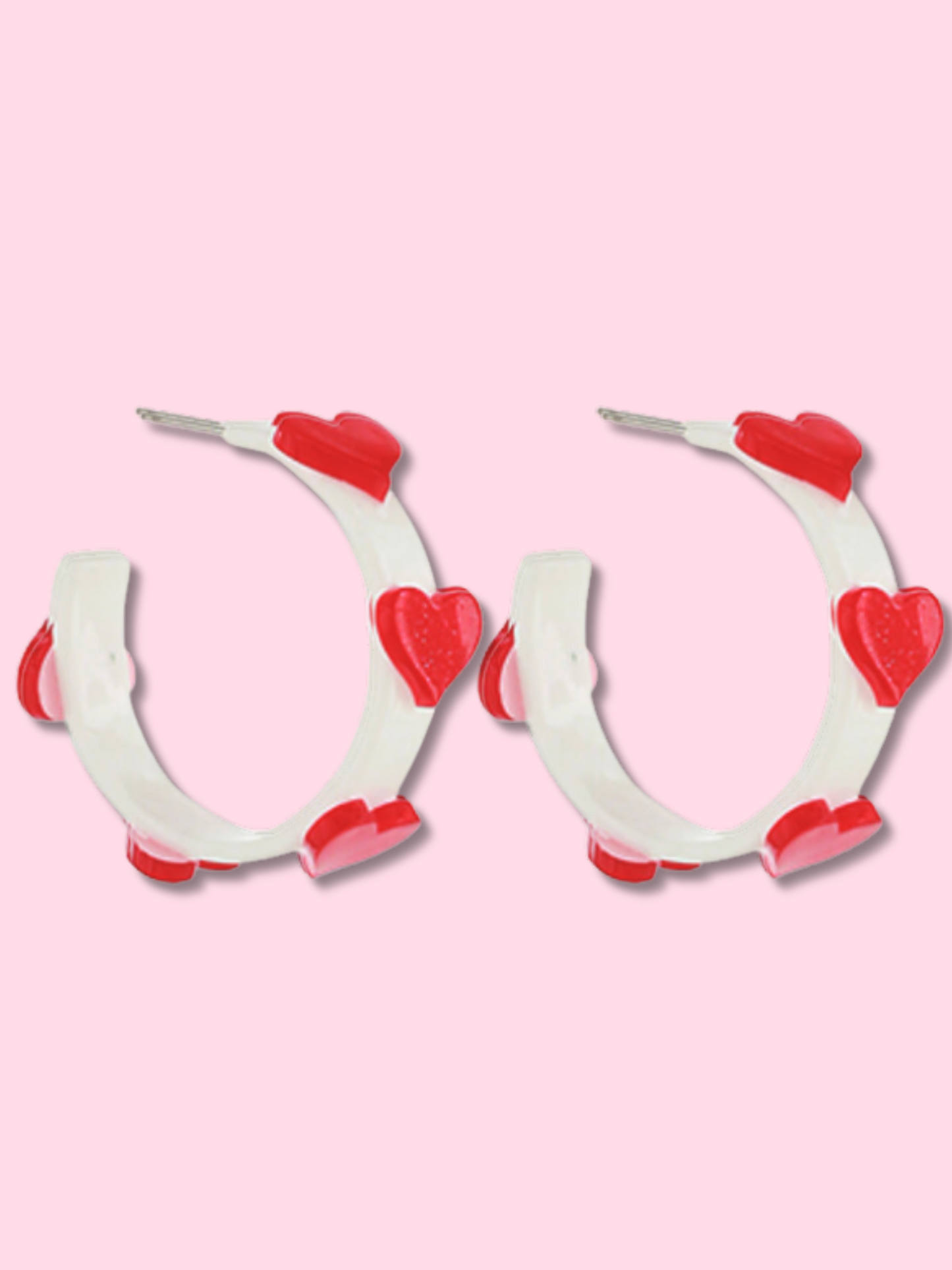 Red and white heart-shaped hoop earrings against a pink background.