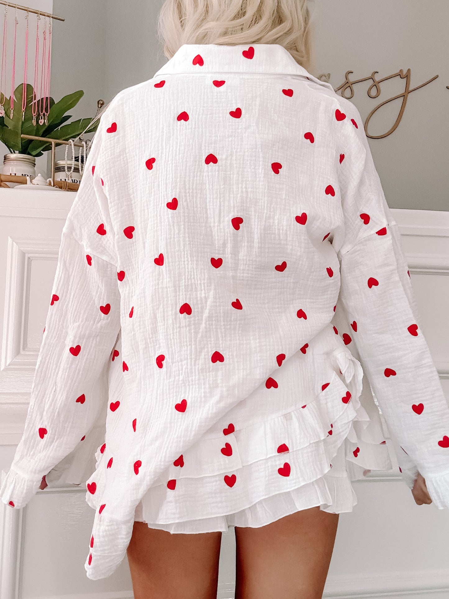 White lounge set with red heart pattern; ruffled shorts and oversized shirt.