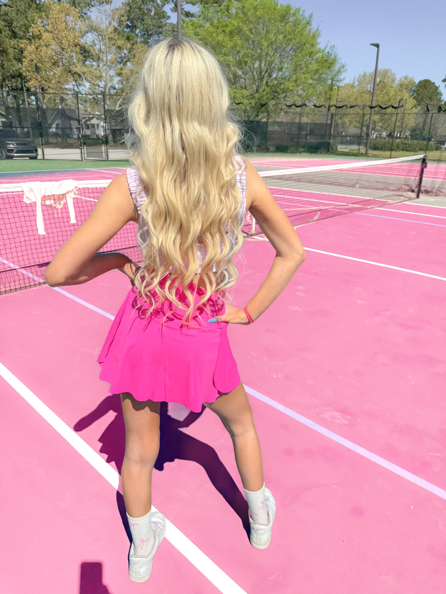 Neon pink pleated mini skirt on a pink tennis court.