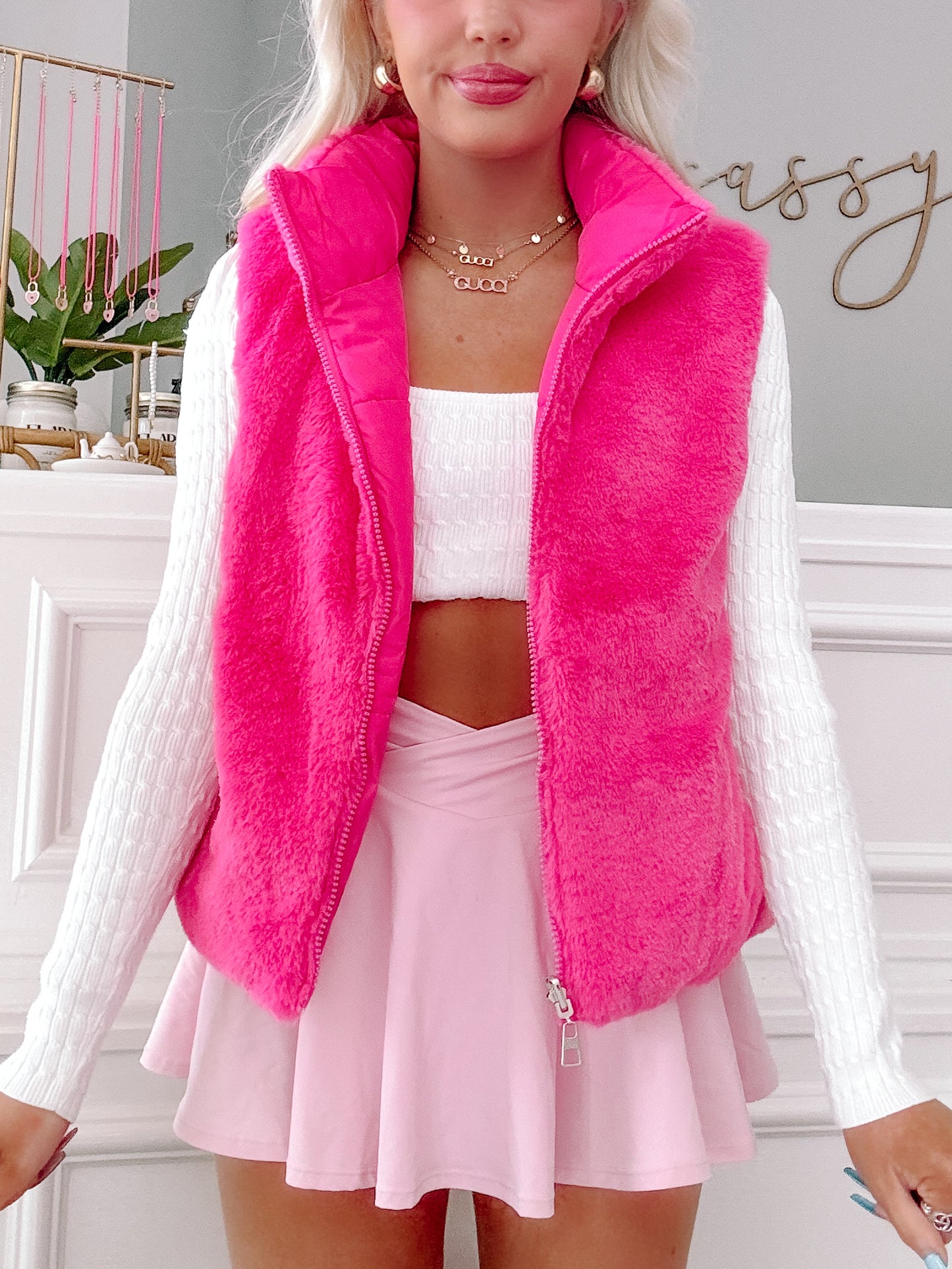 Hot pink faux fur vest styled with a white sweater and pink skirt.