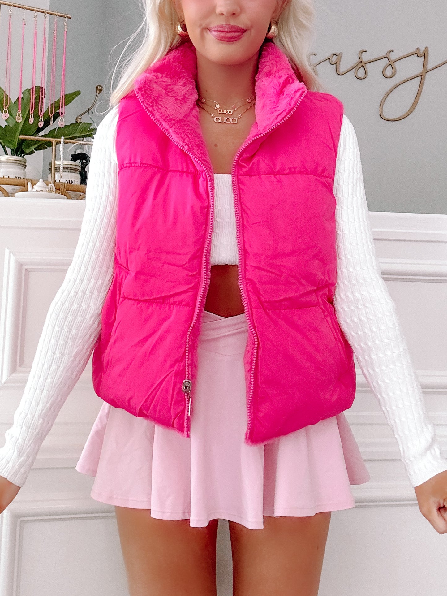 Hot pink puffer vest with fuzzy lining, styled with a white sweater and pink skirt.