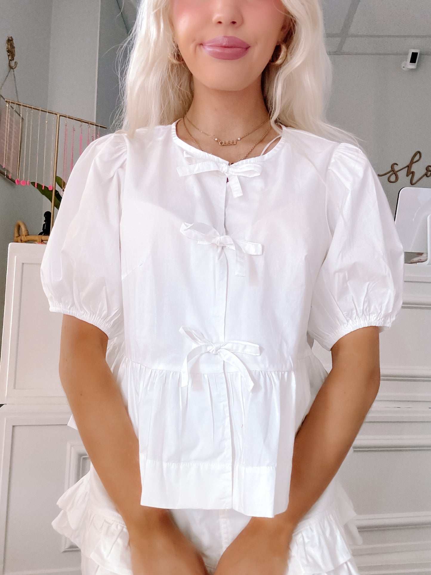 Close-up of bow accents and sleeve detail on white top