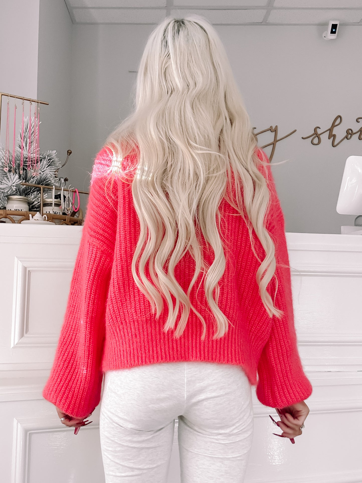 Hot pink knit sweater with balloon sleeves, shown from the back in a bright interior.