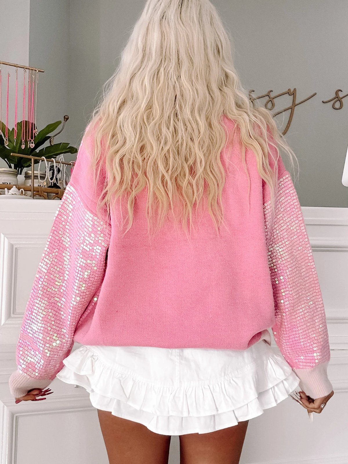 Pink sequined sleeve sweater paired with a white ruffle skirt.