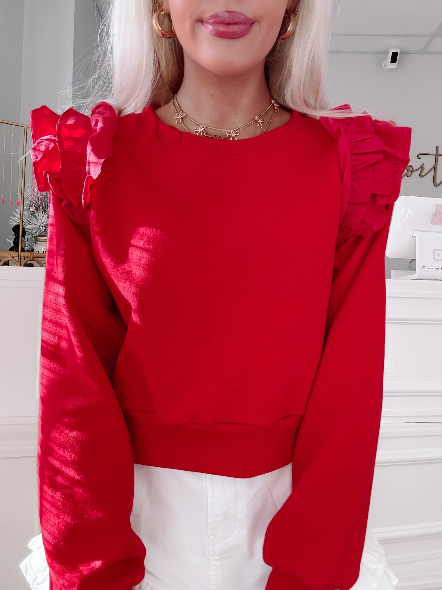 Red cropped sweatshirt with ruffled shoulders, styled with white shorts.