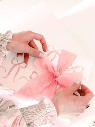 Pink gift wrap with delicate bow, ready for gifting.
