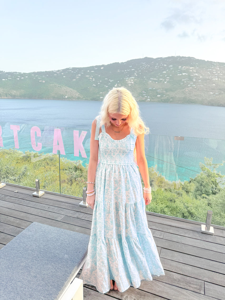 Sassy Shortcake Sweet Pea blue floral maxi with tie shoulders and flowing tiers on oceanfront deck.