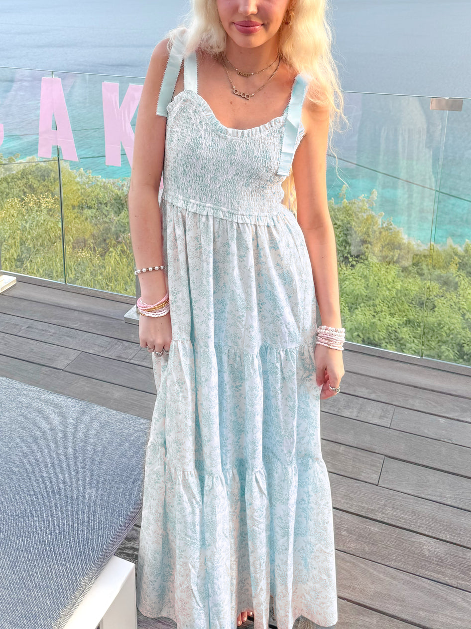 Sassy Shortcake Sweet Pea blue floral maxi dress on balcony — smocked bodice, tie-shoulder bows, tiered skirt