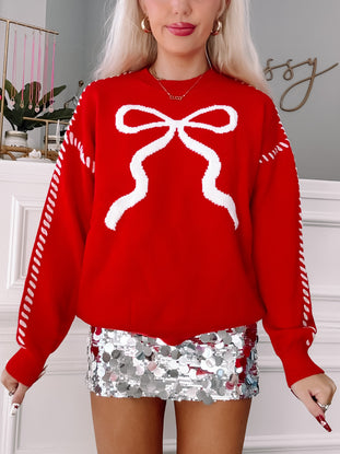 Red knit sweater with white bow detail and white stitching