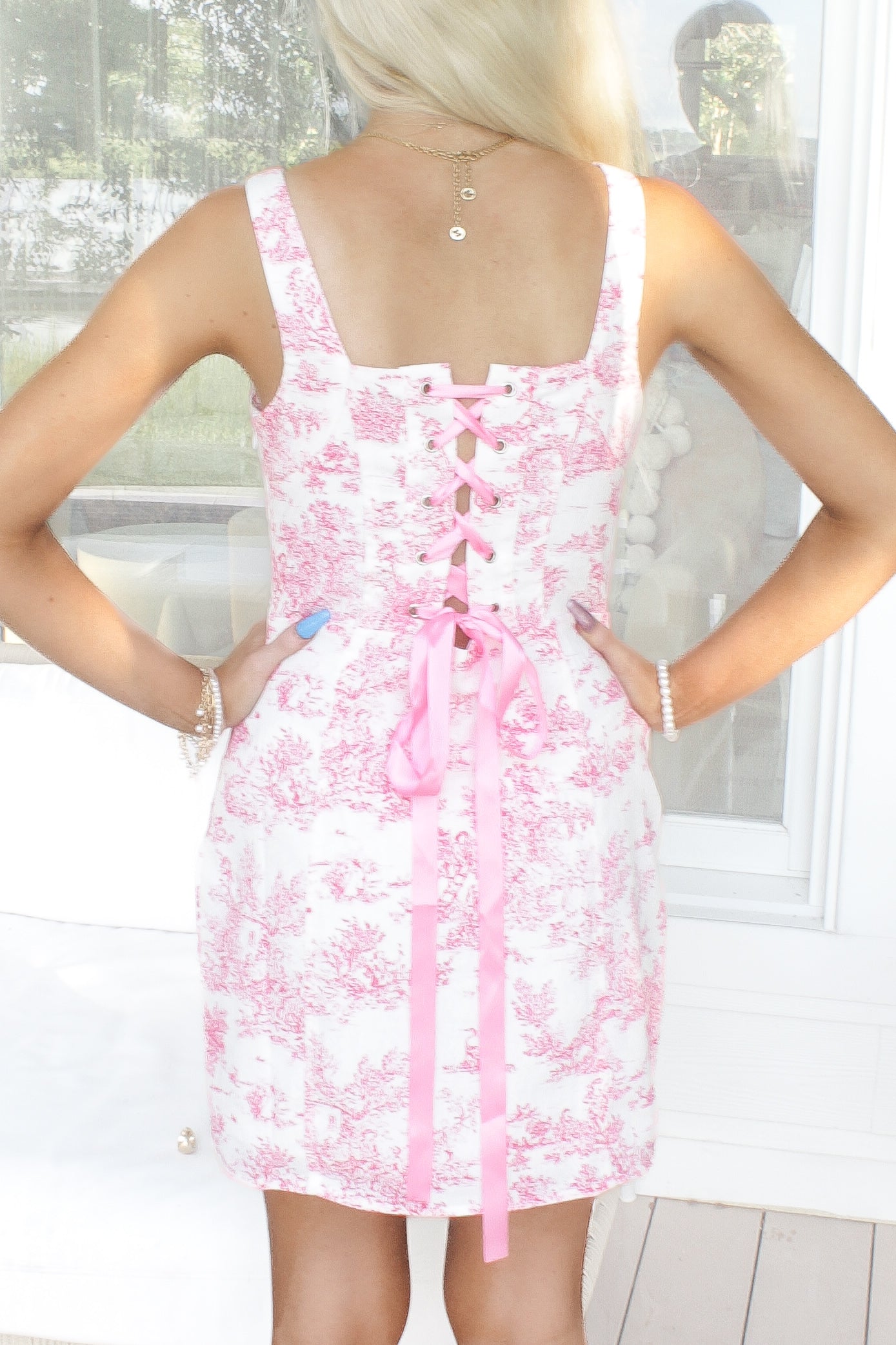 Pink toile print dress with a corset-style back and pink ribbon lacing.