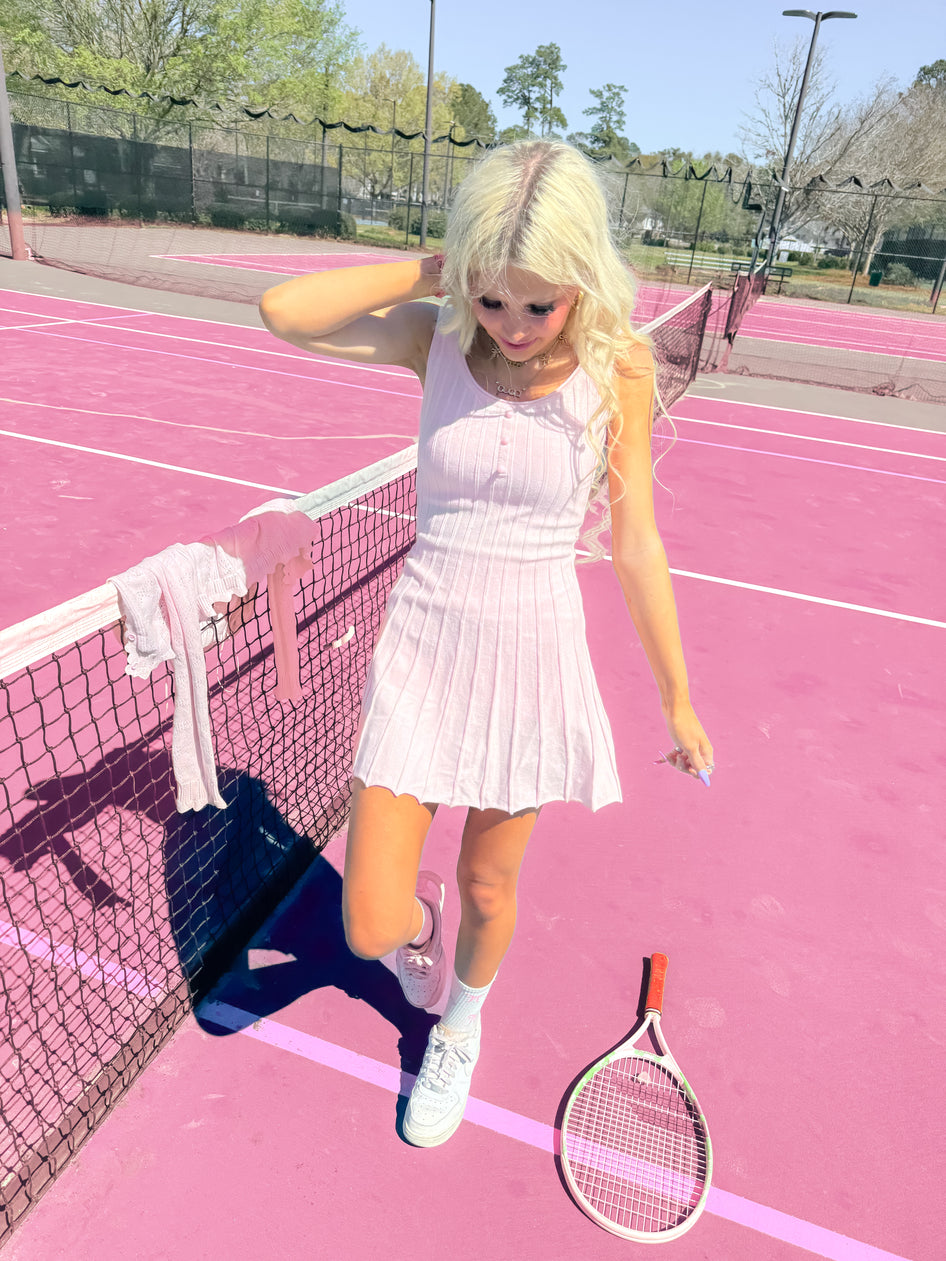 Pink tennis dress on a pink court, sunny day.