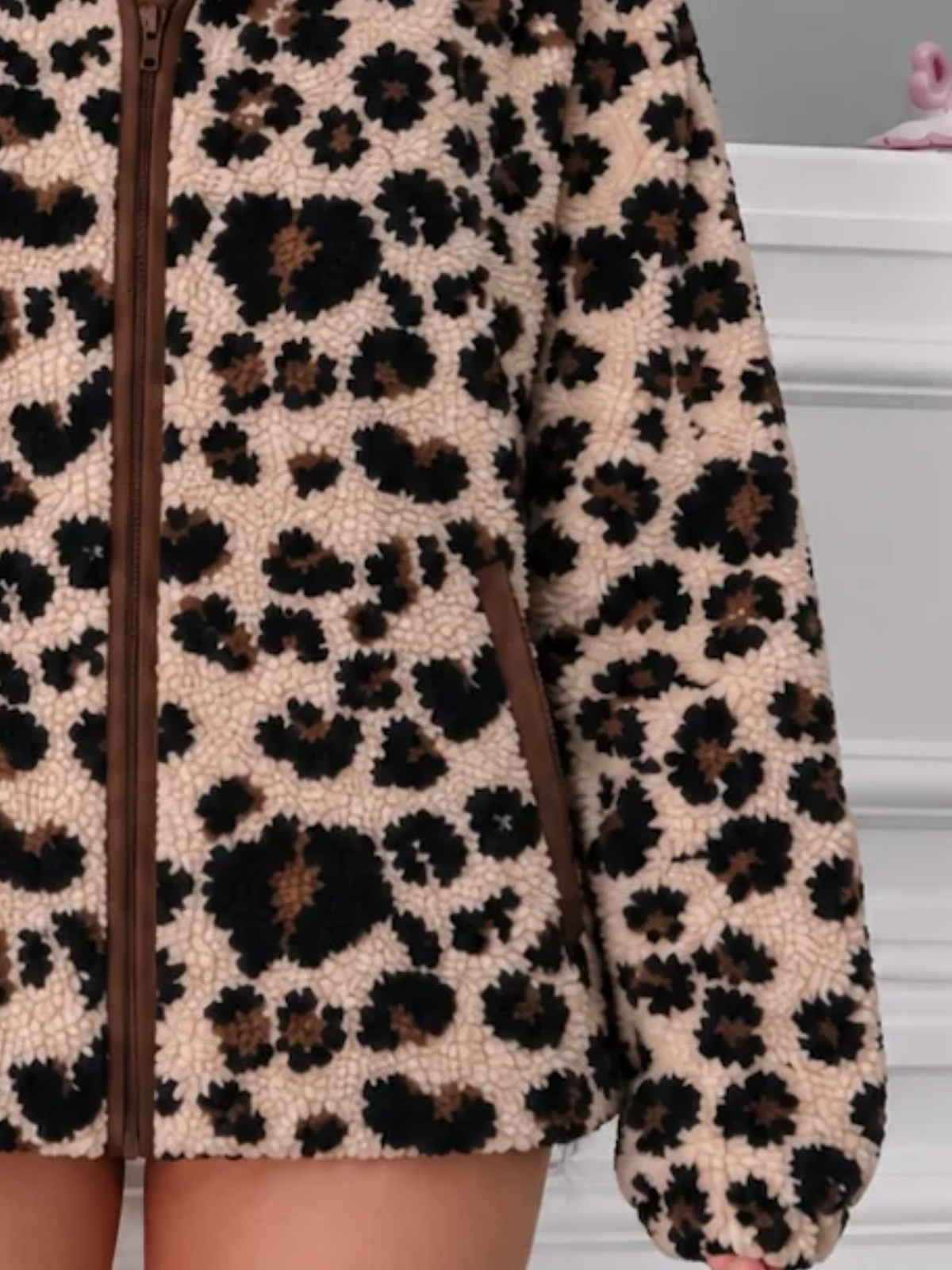 Close-up of the Sassy Shortcake Wild Child Jacket showing the fluffy leopard print teddy texture and chocolate brown zipper trim.